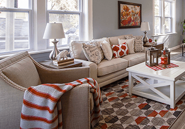 Open living room with hardwood, a white couch and red accents