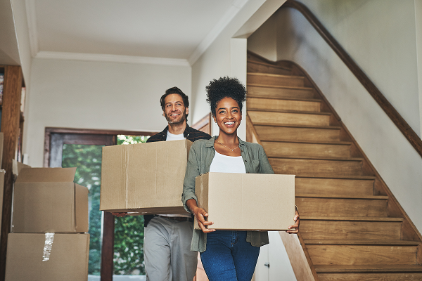 man and woman walking into their new house with moving boxes