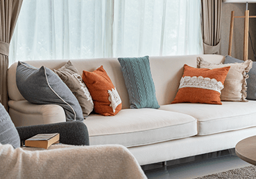 Fabric beigh couch with orange and yellow pillows
