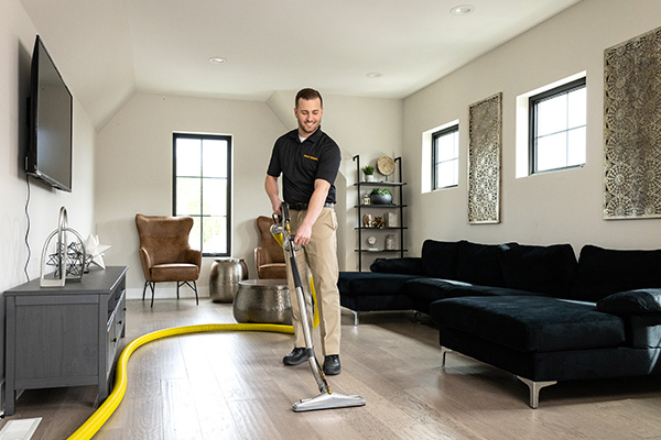 tech using cleaning wand to clean living room lvp floor