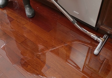 Water flooding out of a dishwasher on a kitchen floor. 