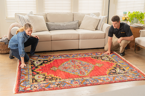 Stanley Steemer technician inspecting rug with customer